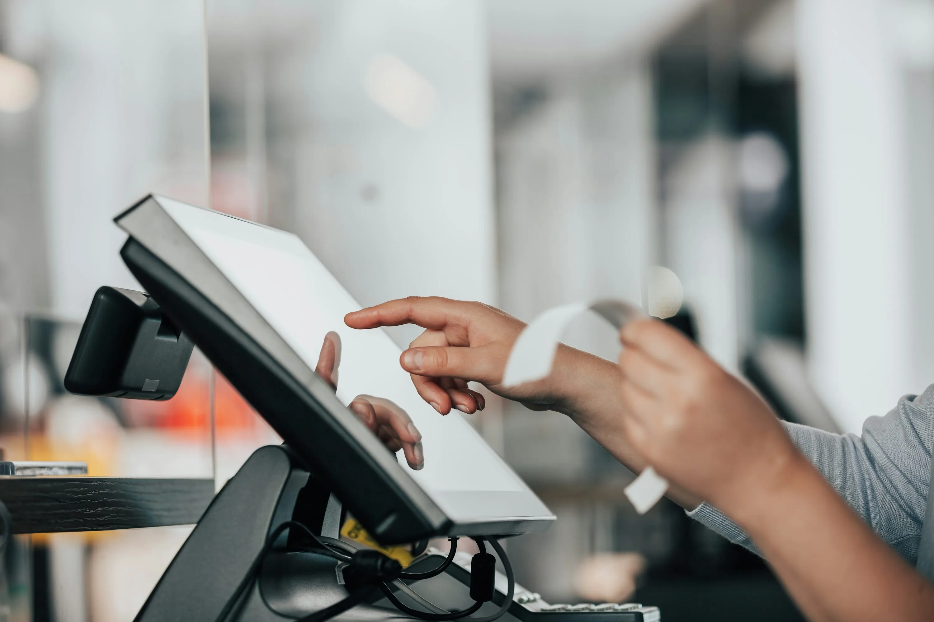 Hands using a point of sale terminal and receipt printer in a retail setting
