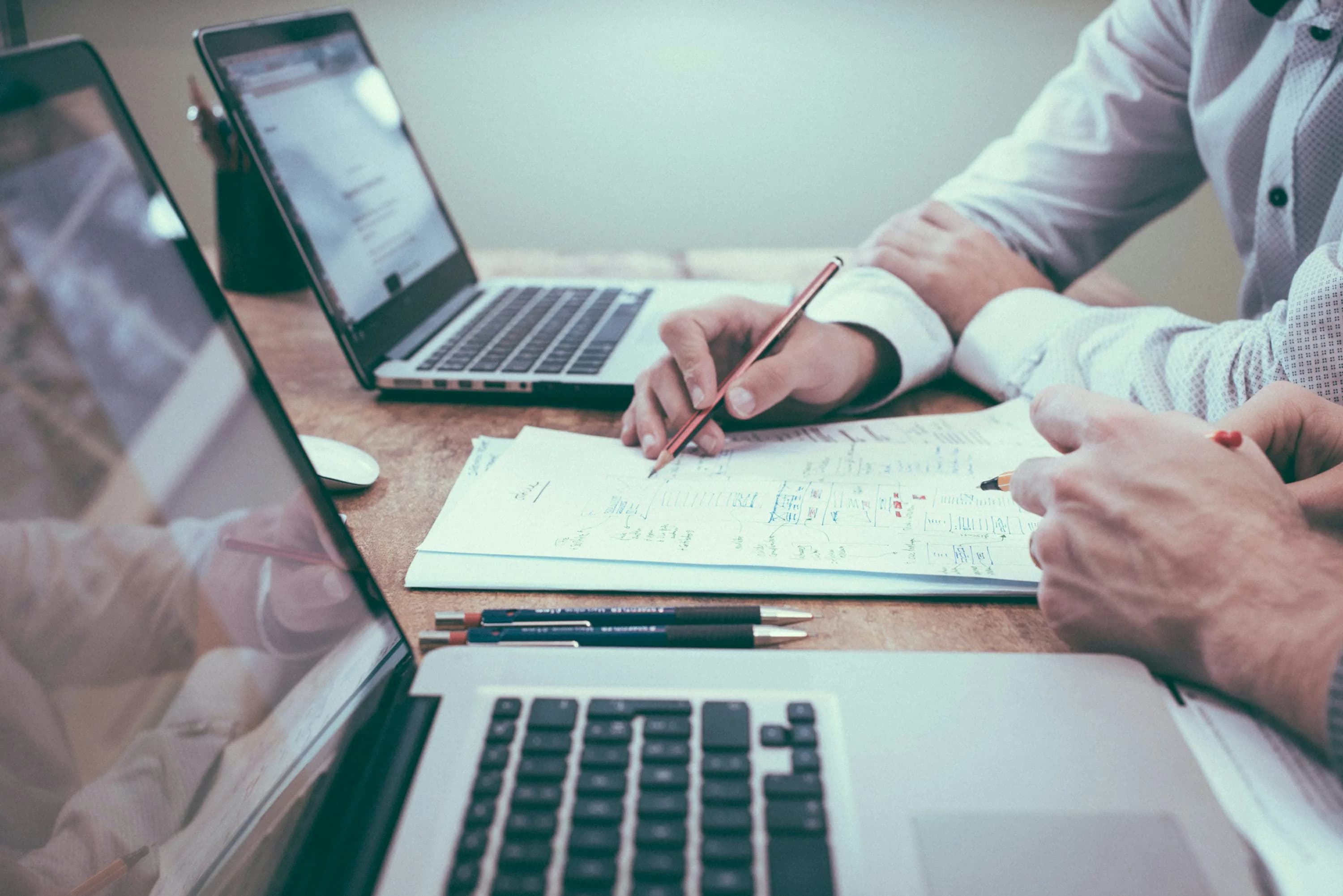 Person reviewing spreadsheet data beside a laptop, representing a business that has outgrown spreadsheets